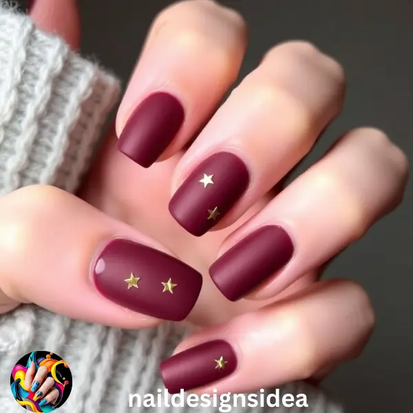 Matte burgundy nails provide a soft, sophisticated look with a holiday twist. Adding tiny gold stars on a couple of nails transforms this color into a festive, dark Christmas nail design. 